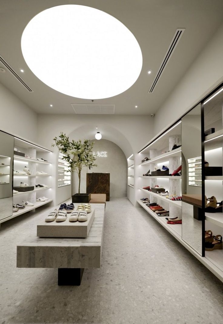 a room filled with lots of white shelves and shoes on top of each other in front of a round ceiling light