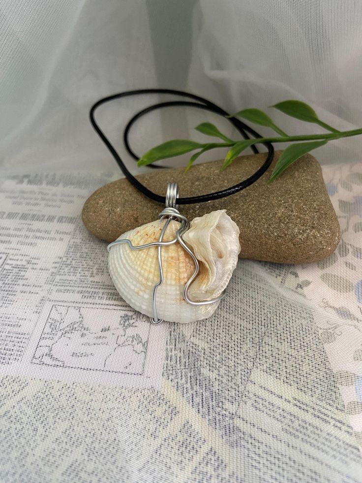 This simple but elegant necklace is made from a white seashell that is wire wrapped and hung on an 18" wax cord necklace with a 2" extension chain for adjusting the size. This shell has a unique shape to it and is just so beautiful! It makes the perfect addition to any summer outfit and any beach day! Orders within Canada are sent via oversized lettermail (no tracking) to keep shipping costs low. Tracking is available at the checkout for an extra fee.  Orders to the US are sent via tracked packe White Sterling Silver Shell Necklace For Gift, White Sterling Silver Shell Necklace As Gift, White Sterling Silver Shell For Beach, Adjustable Ocean-inspired Shell Pendant Necklace, White Waxed Cord Beach Jewelry, White Waxed Cord Jewelry For Beach, White Waxed Cord Jewelry For The Beach, Beach Shell Necklace Wire Wrapped, Wire Wrapped Shell Necklace For Beach