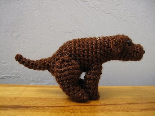 a small crocheted dog on a wooden table next to a white painted wall