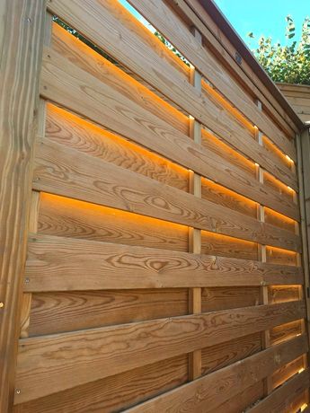 a wooden fence with lights shining on it's sides and behind it is a tree