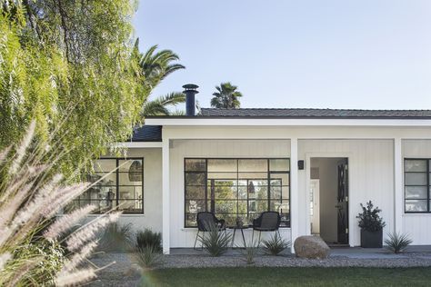 a small white house with palm trees in the front yard and grass on the lawn