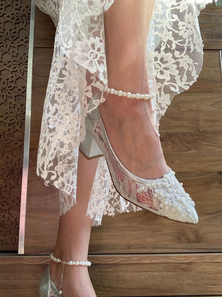 a close up of a woman's shoes on top of a wooden floor with lace