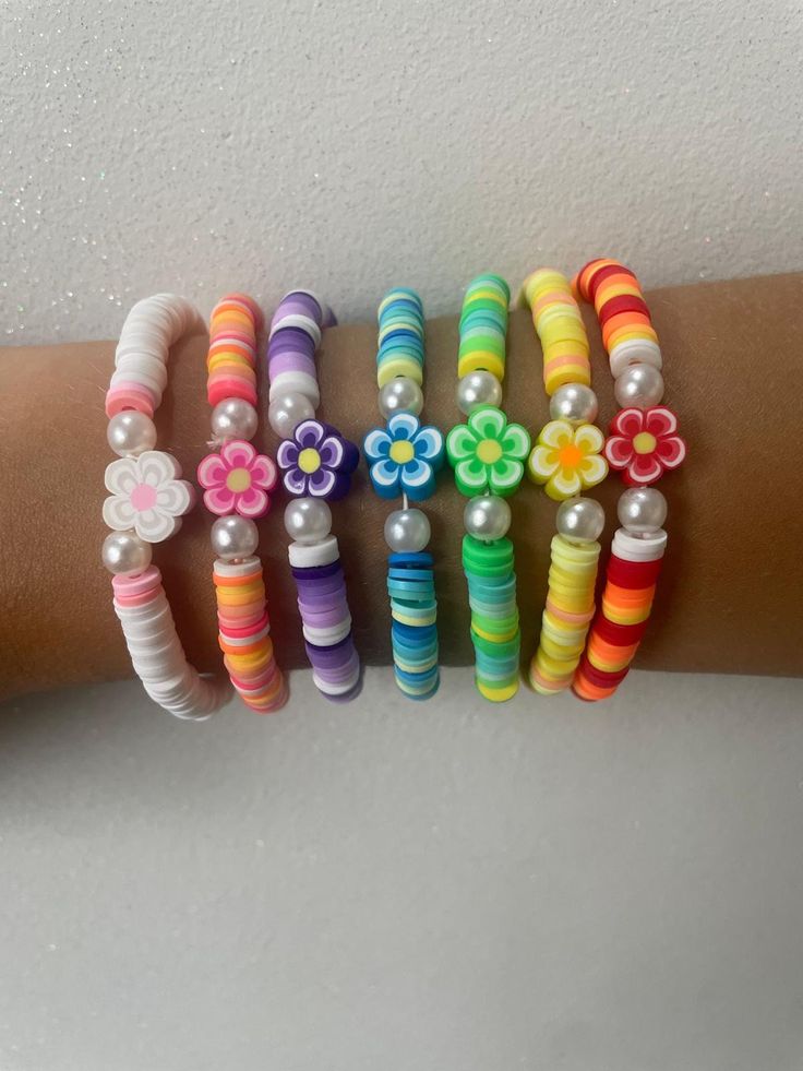 a woman's arm with several bracelets and flowers on the wrist, all in different colors