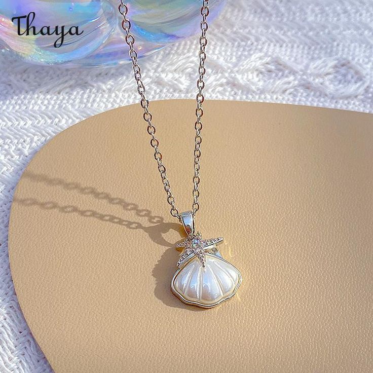 The Coastal Charm Shell Necklace is a delightful and whimsical piece of jewelry inspired by the beauty of the coast and the treasures of the sea. This necklace features real or crafted shells that evoke a sense of beachy charm and coastal allure.  - Brand: Thaya  - Material: Titanium Steel  - Size: Chain length 40+5cm  - Shape: Shell  - Gender: Women's White Ocean-inspired Charm Necklace For Gift, Ocean-inspired White Charm Necklace As Gift, Ocean-inspired White Charm Necklace Gift, Gift Ocean-inspired Shell Necklace With Starfish Charm, Ocean-inspired Shell Pendant Necklace With Lobster Clasp, Shell-shaped Ocean-inspired Jewelry With Starfish Charm, Ocean-inspired Shell Necklace With Pearl Charm, Ocean-inspired Shell-shaped Necklace With Pearl Pendant, Ocean-inspired Shell Necklaces For Gifts