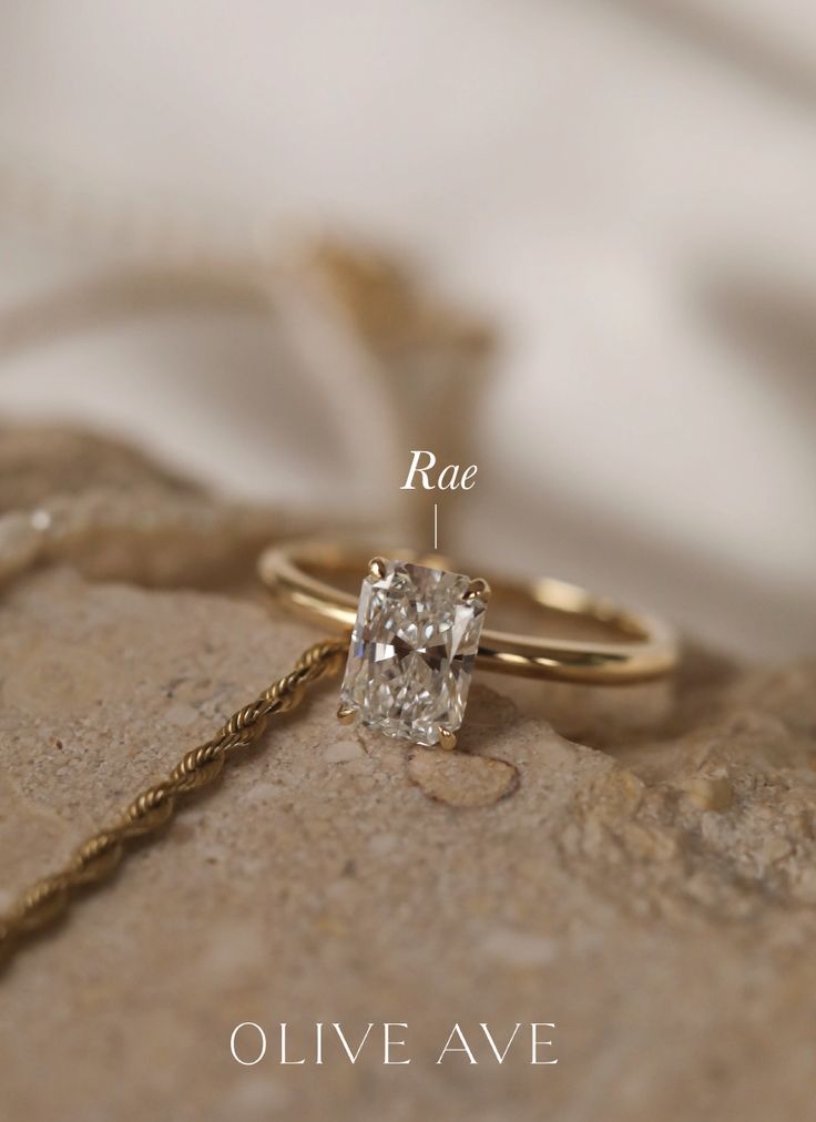 an engagement ring with a square cut diamond in the center, on top of a rock