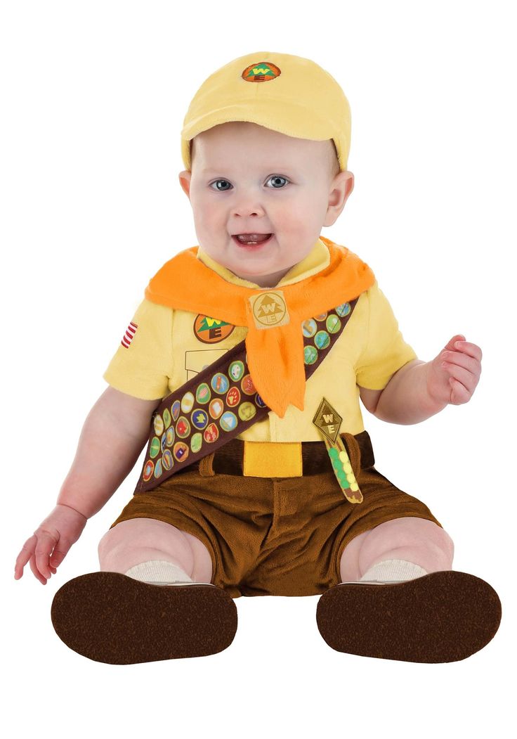 a baby sitting on the ground wearing a yellow shirt and brown pants