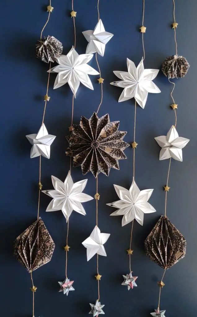 an origami star mobile is hanging on the wall with other ornaments around it