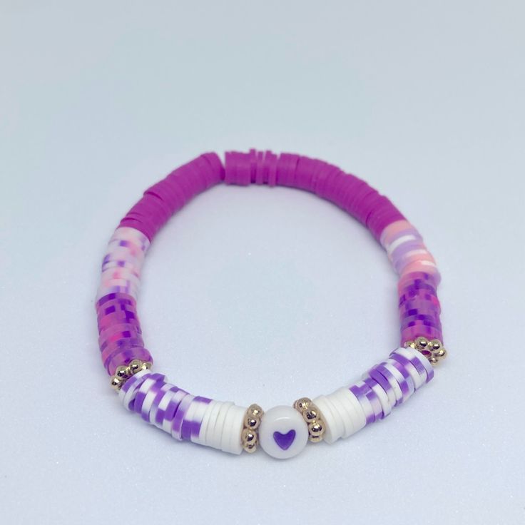 a purple and white beaded bracelet with heart charms on it's end, against a white background