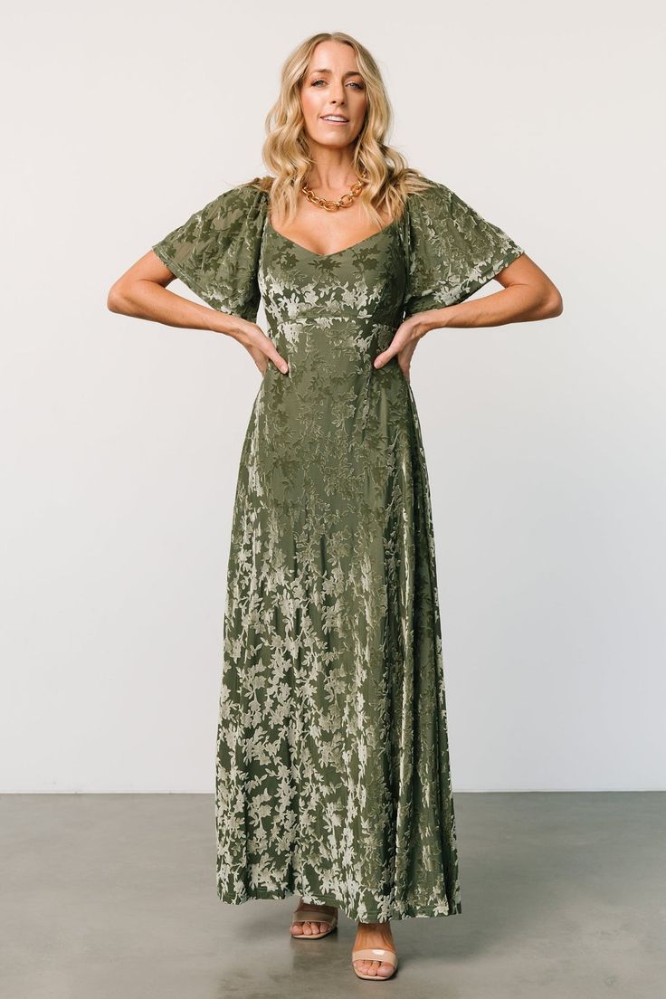 a woman in a green dress posing for the camera with her hands on her hips