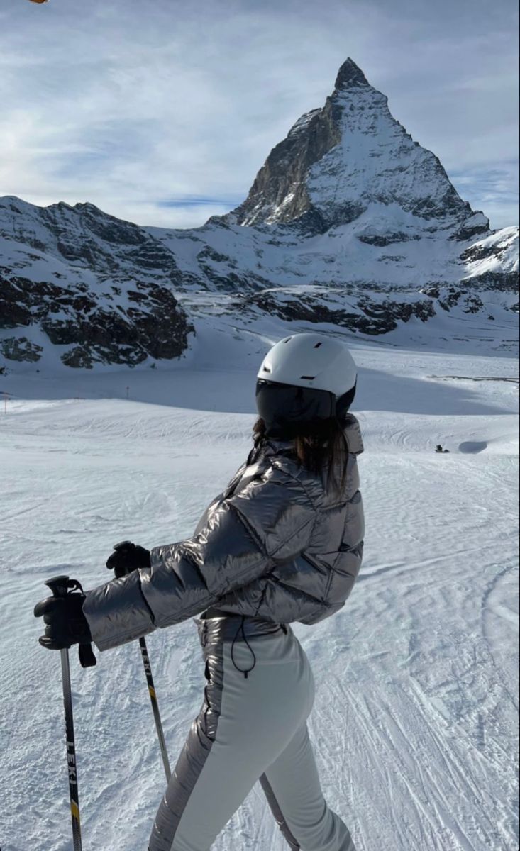 a woman on skis in the snow with mountains in the backgrouund