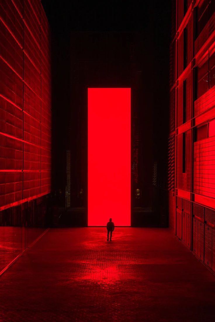 a person standing in an empty room with red lights on the walls and flooring