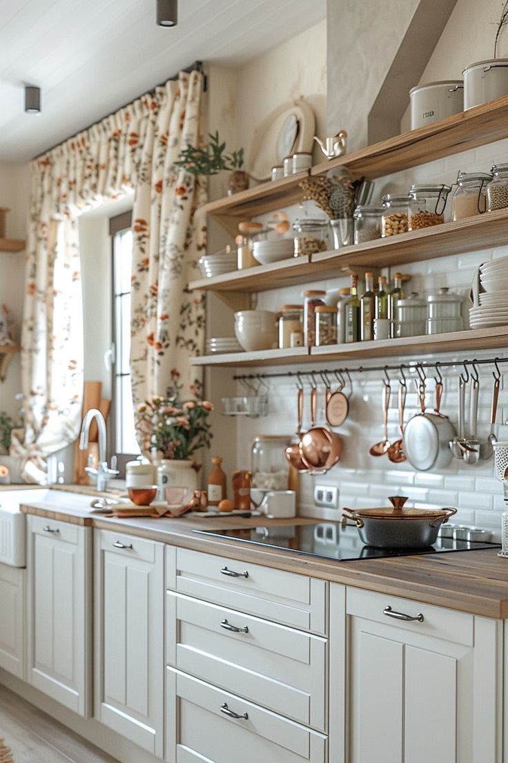 a kitchen filled with lots of white cupboards and counter top covered in pots and pans