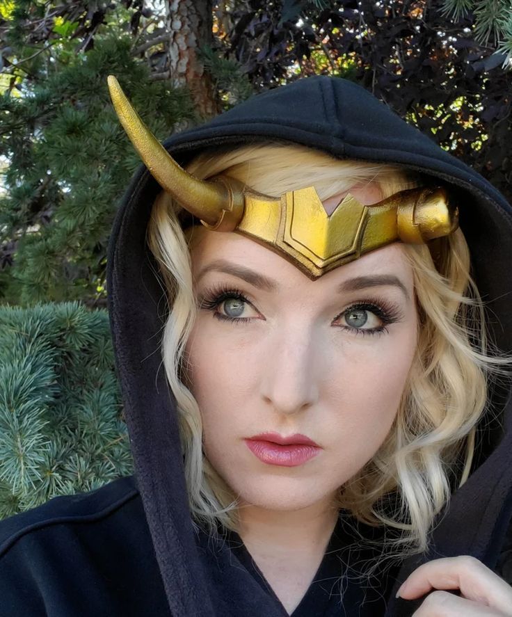 a woman wearing a hoodie with horns on it's head and a cape around her neck