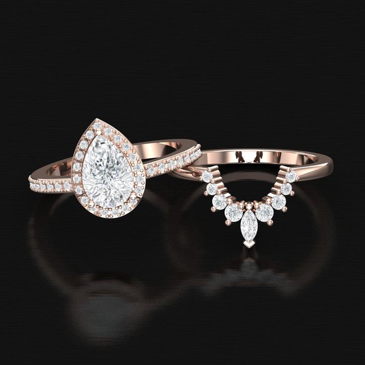 two engagement rings with pear shaped diamonds on black background