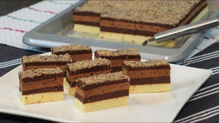 several pieces of cake sitting on a plate next to a tray with other desserts