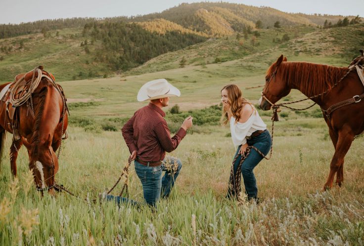 two women and a man standing in a field with horses