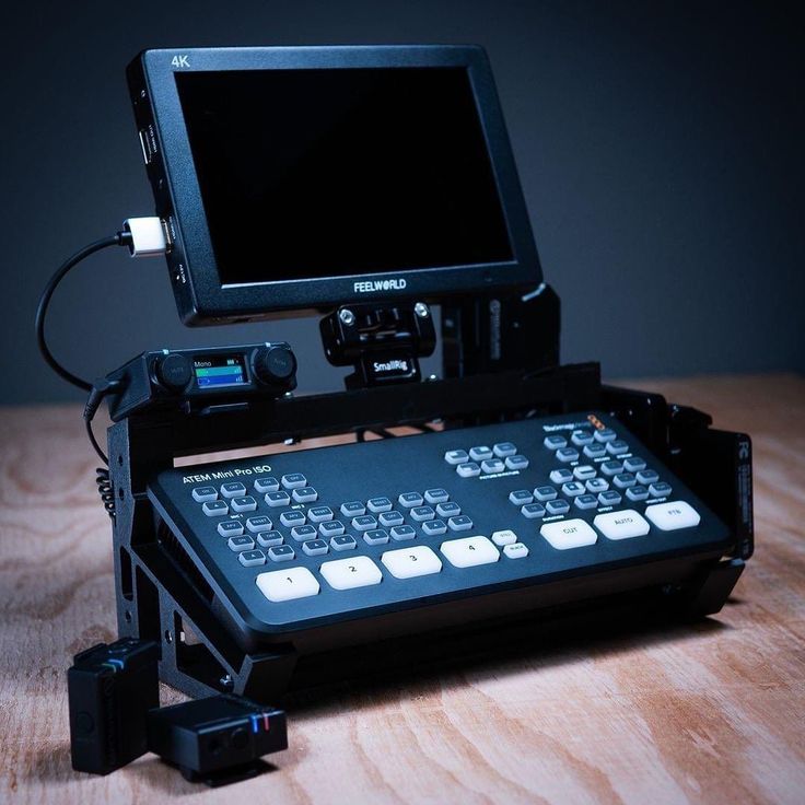 a camera sitting on top of a wooden table next to a computer monitor and keyboard