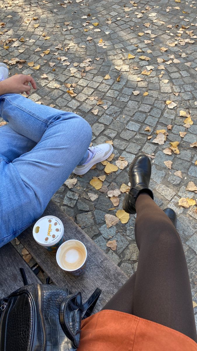 two people sitting on a bench with their feet propped up against each other's legs