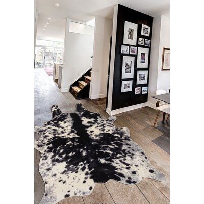 a living room with pictures on the wall and cow hide rug in front of it