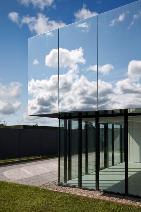 an empty building with glass walls on the outside and sky in the backround