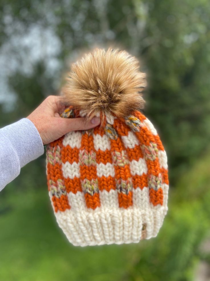 Ready To Ship! Adult sized Classic Cozy Buffalo Plaid Beanie.  Colors are from Lion Brand Yarn called Fisherman (brim), Pumpkin & Coney Island, all super bulky yarns.  They blend nicely together to create this beautiful Buffalo Check.  Luxurious Faux Fur Pom is called Toasted Marshmallow. These are very warm for the cold winter days.  The yarn is 20% wool, 80% acrylic.  Fits head circumference from 19-23" so will fit teen to adult sized head.  Made in a smoke-free home.     Spot clean only! Pattern by Me! You can find this pattern here if you'd like to purchase it: https://www.etsy.com/listing/923495930/cozy-buffalo-plaid-beanie-knitting Chunky Knit Beanie For Fall, Acrylic Beanie For Fall, Knit Beanie For Fall, One Size Fits Most, Fall Acrylic Hand Knitted Beanie, Brown Knitted Beanie For Fall, Cozy Knit Hat For Fall Season, Cozy Knitted Hats For Fall, Cozy Knit Hat For Fall, Cozy White Beanie For Fall