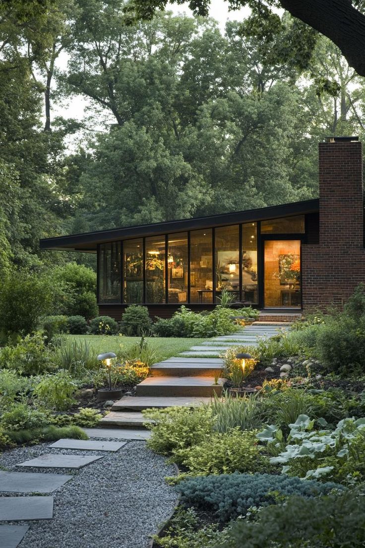 a modern house surrounded by greenery and stone steps leading up to the front door