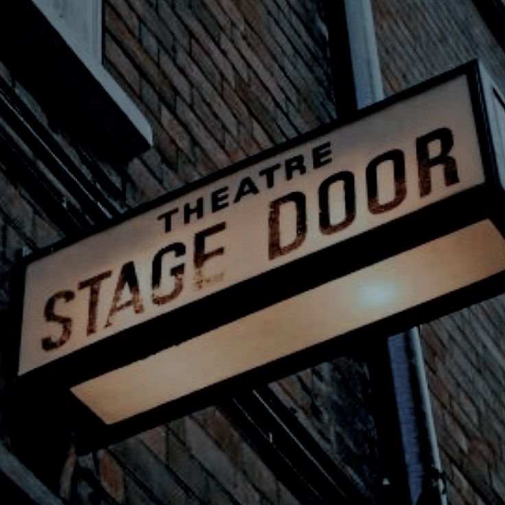 the theatre stage door sign is hanging from the side of a building with brick walls