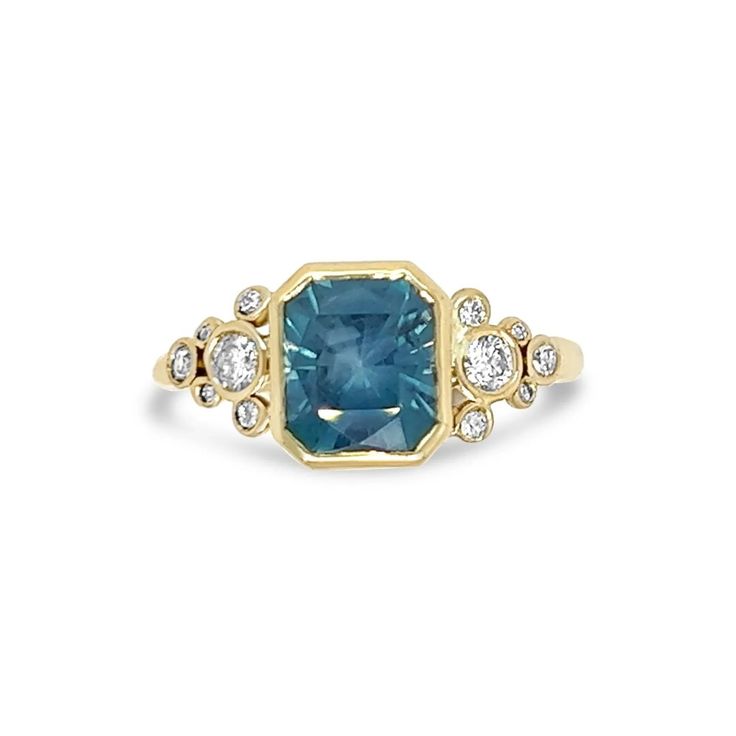 a blue and white diamond ring with two diamonds on the sides, set in yellow gold