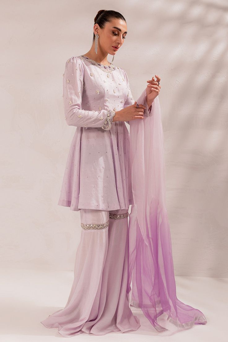 Pakistani Eid Dress in Lilac Gharara and Peplum Style is a stunning masterpiece that will give you a head-turning look on the festive occasion. This beautiful Gharara Dress is embellished with crystals, Resham, and sequins, making it an epitome of beauty and grace. Detailed Description: SKU: PS1831 Detailing: Embroidery, Threads, Crystals, Resham, Sequins Color: Lilac Fabric: Raw Silk, Organza Design: Fully Embroidered dress Event: Festive, Party wear Hand Embellished Organza Sharara For Diwali, Organza Dresses Hand Embellished For Diwali, Diwali Hand Embellished Organza Dresses, Diwali Hand-embellished Organza Dresses, Diwali Hand Embellished Georgette Sharara, Purple Embellished Sharara For Eid, Purple Organza Dress For Eid, Elegant Purple Organza Anarkali Set, Embellished Purple Sharara For Eid