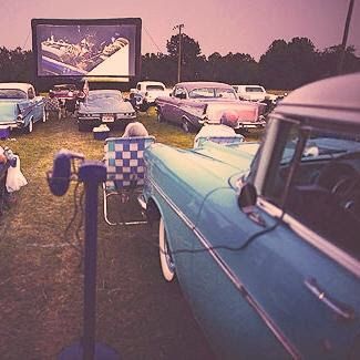 people sitting in lawn chairs watching movies at an outdoor movie theater with cars parked on the grass