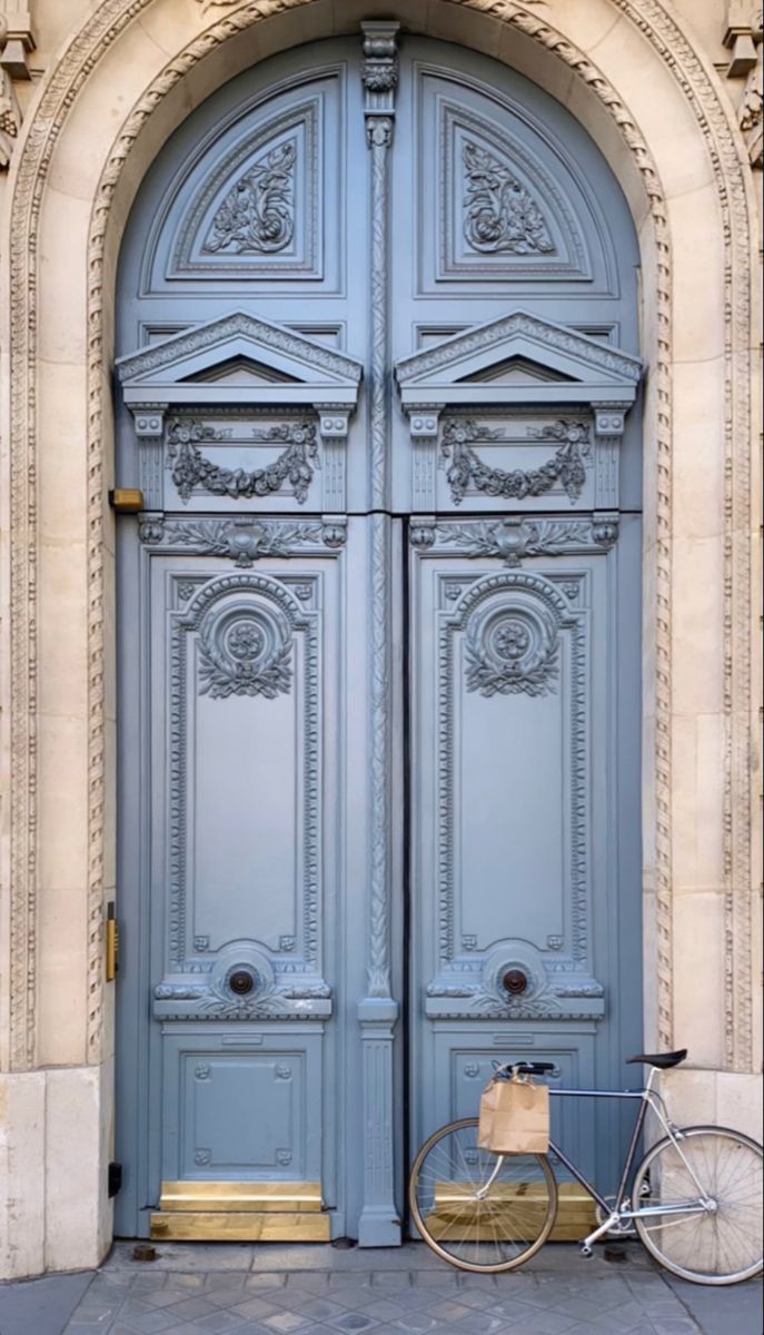 a bicycle parked in front of a blue door with ornate carvings on the doors and sides