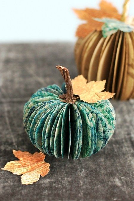 an origami pumpkin sitting on top of a table next to some autumn leaves