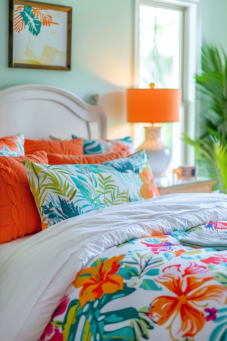 a bed with orange and blue pillows in a bedroom next to a window, palm tree