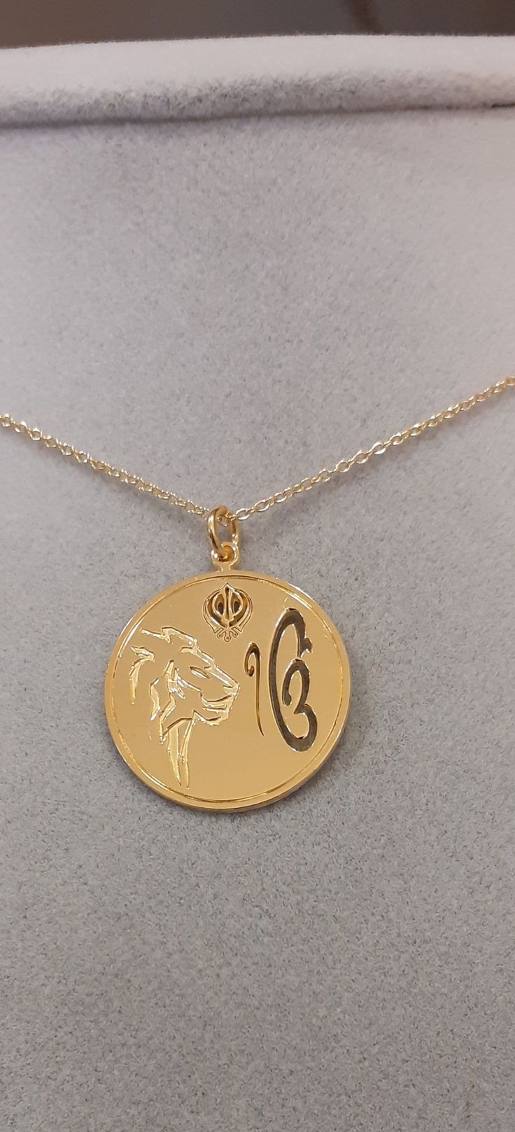 Are you looking for a special gift? How about this precious sterling silver pendant representing the Ik Onkar symbol, the Khanda sword, and the Lion? The Ik Onkar Symbol is the declaration of unity in Sikhism, that is 'there is only one God'. Ik Onkar are the first words of the Mul Mantar and also the opening words of the sacred Sikh scripture Guru Granth Sahib. The double-edged Khanda sword is a metaphor for Divine Knowledge, its sharp edges can separate truth from falsehood. Outside the circle Commemoration Jewelry With Large Pendant, Symbolic Coin Jewelry For Good Luck, Symbolic Medallion Jewelry For Commemoration, Symbolic Jewelry With Large Coin Pendant, Symbolic Coin-shaped Jewelry With Large Pendant, Symbolic Large Coin Pendant Jewelry, Symbolic Medallion Necklace For Commemoration, Symbolic Engraved Jewelry For Commemoration, Symbolic Good Luck Jewelry With Coin Pendant