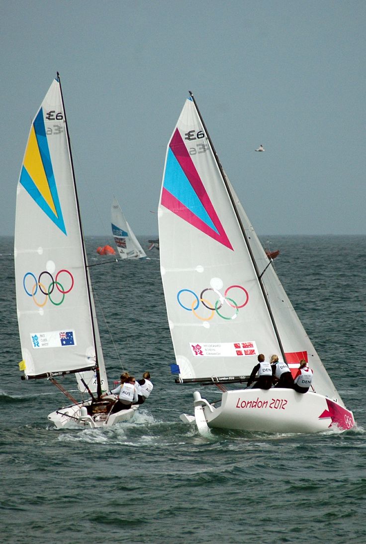 two sailboats in the water with olympic symbols on their sails