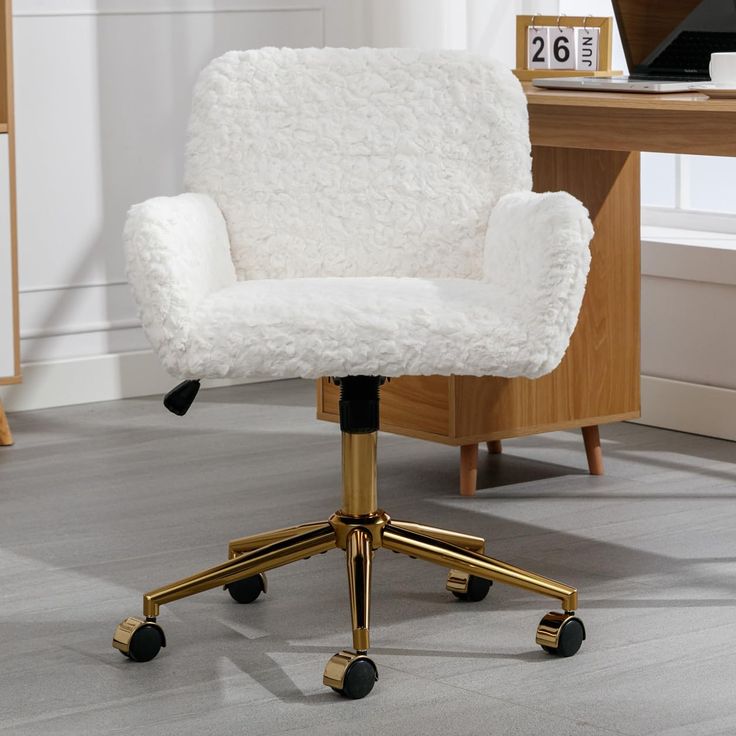 a white chair with gold wheels in front of a desk