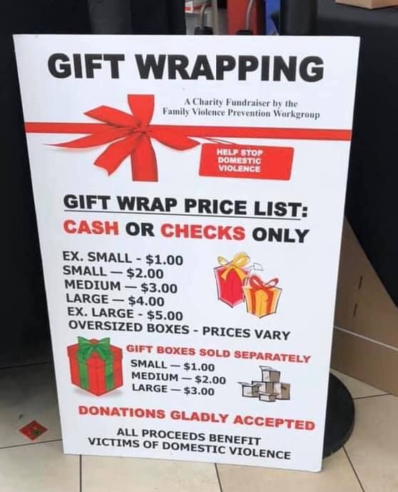 a sign that is sitting on the ground near some boxes and presents in front of it