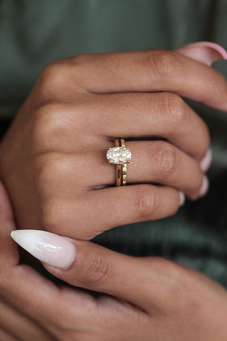 a woman's hand holding an engagement ring with a diamond on the middle finger