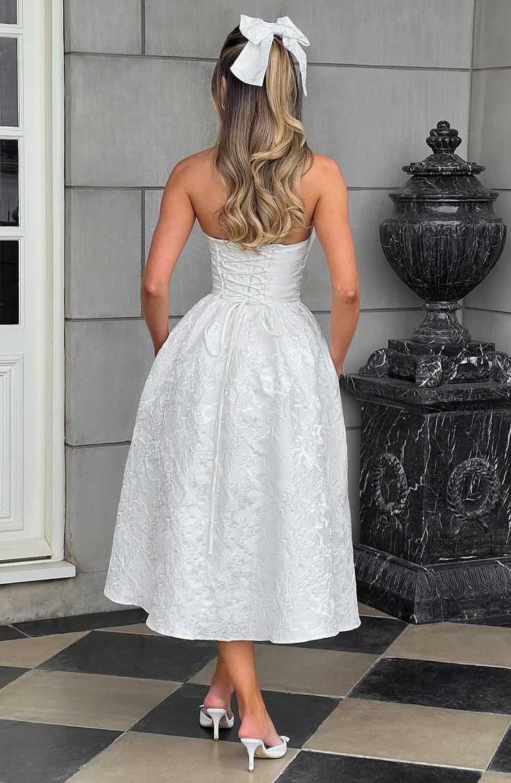 a woman in a white dress standing on a black and white checkered tile floor