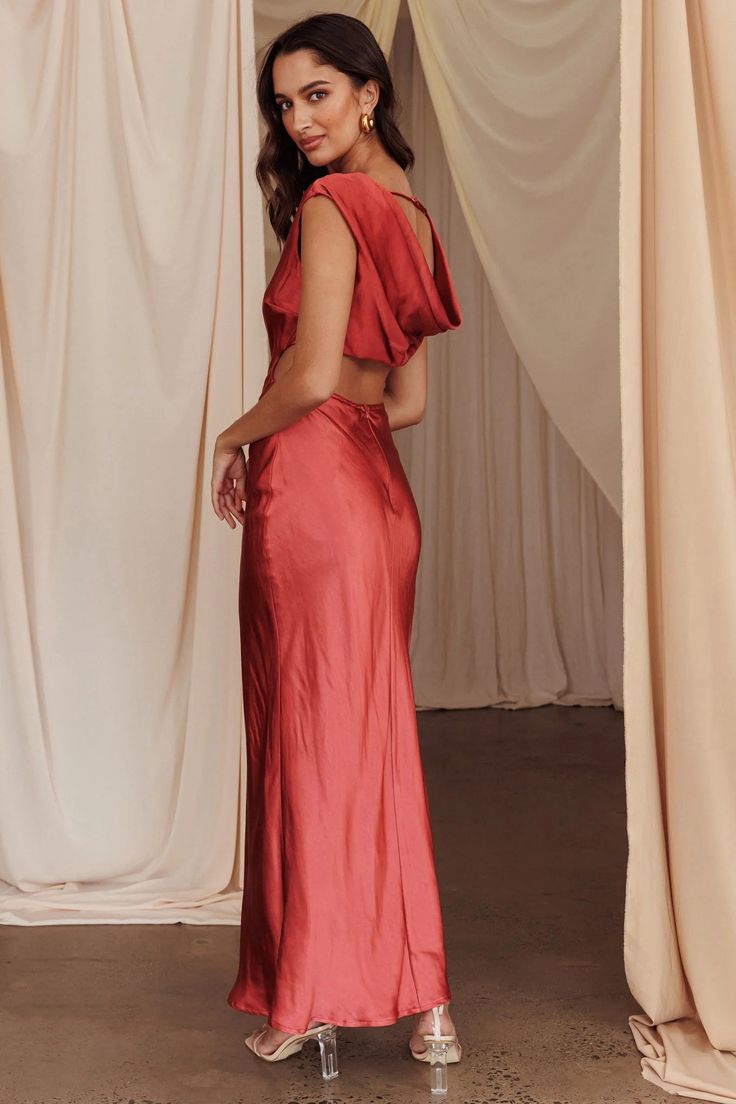 a woman standing in front of curtains wearing a red dress