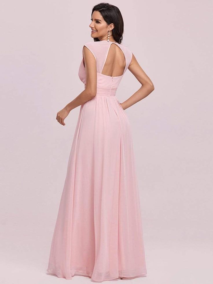 a woman in a long pink dress is standing and looking at the back of her dress