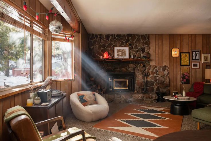 a living room filled with furniture and a fire place next to a stone covered wall