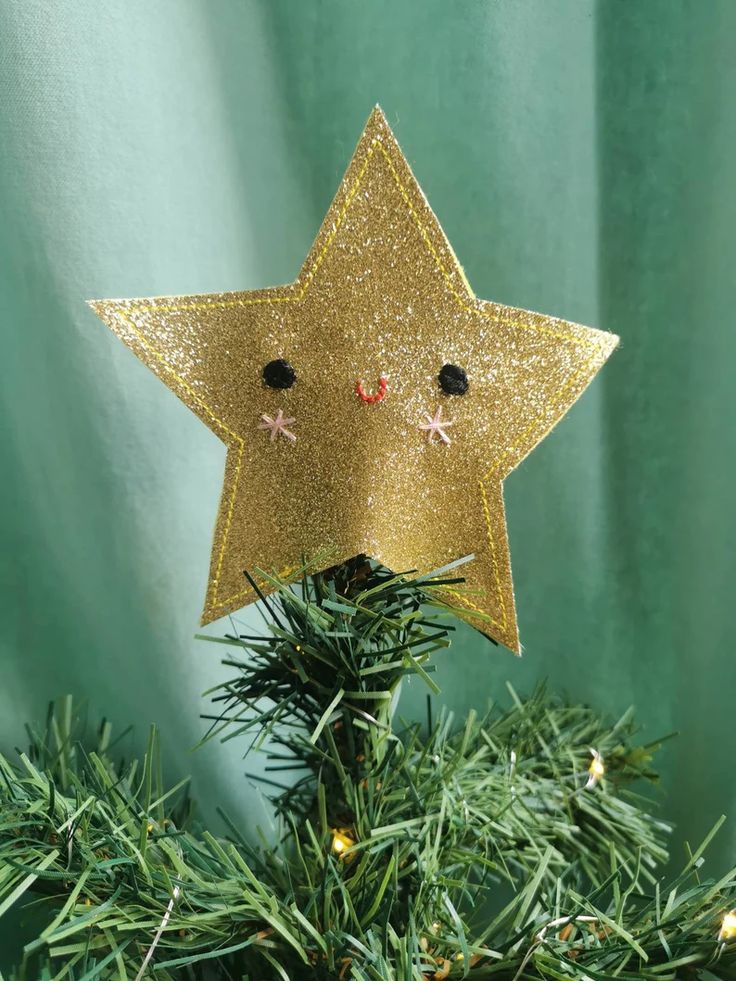 a gold star ornament on top of a christmas tree with eyes and nose