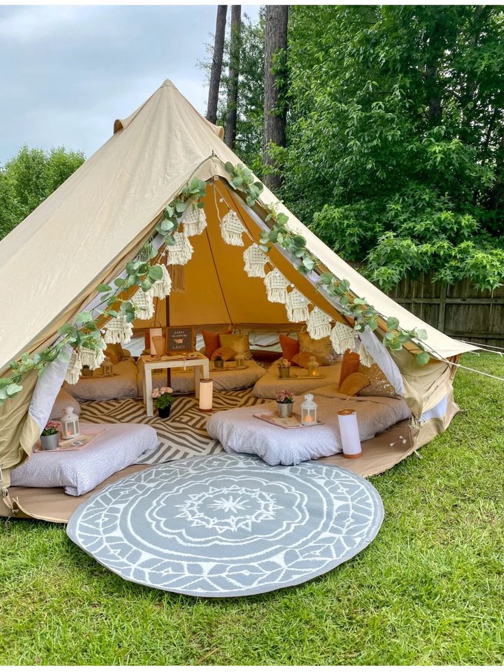 a tent with pillows and blankets on the grass