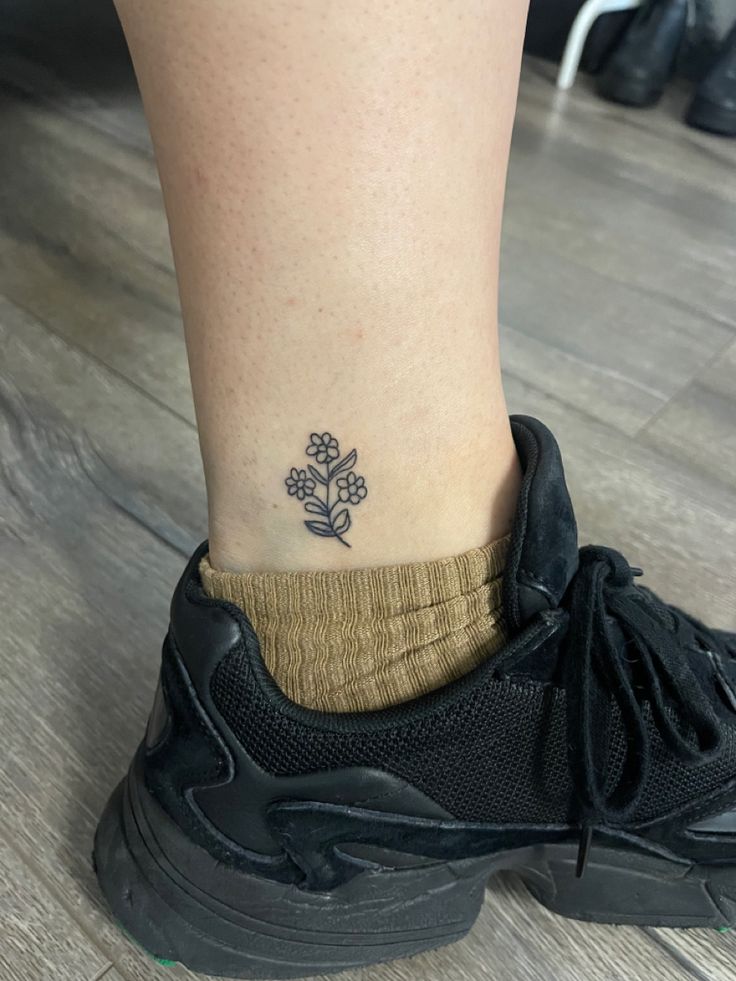 a small flower tattoo on the ankle