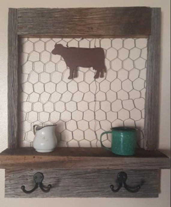 a wooden shelf with two hooks on it and a cow cut out in the middle