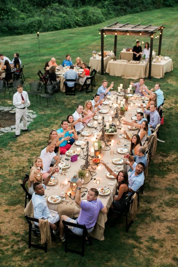 a group of people sitting around a long table with plates and candles in front of them