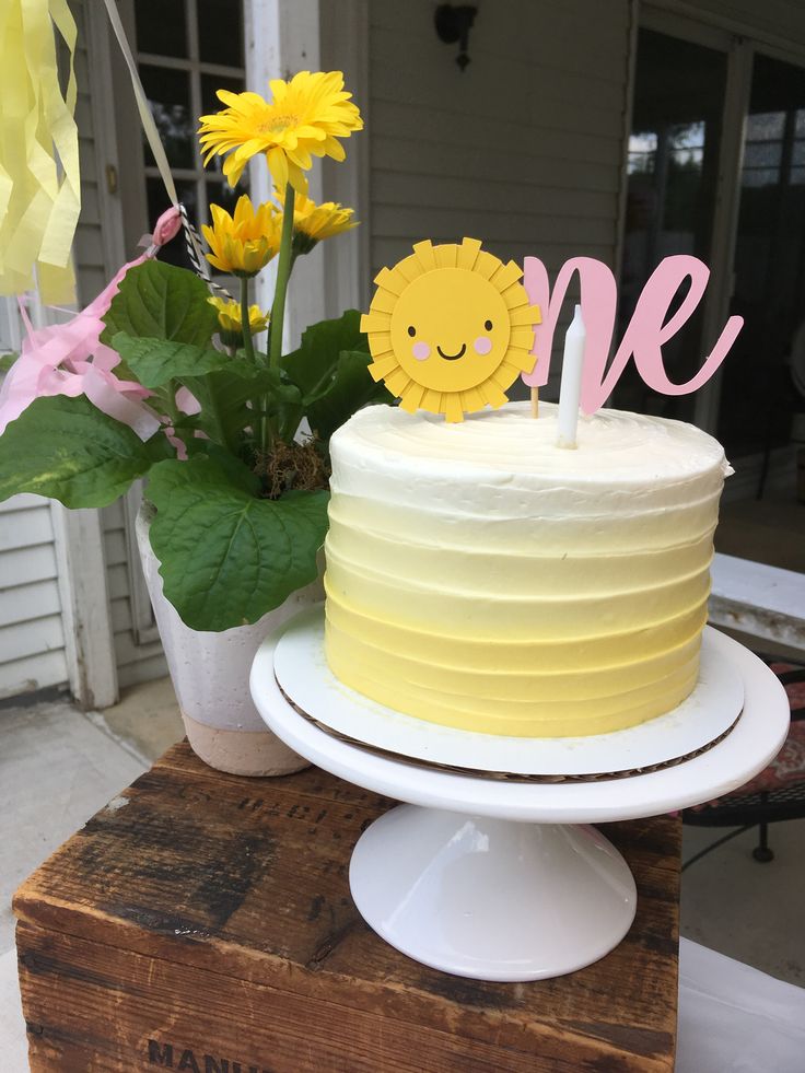 a yellow cake sitting on top of a wooden table next to a potted plant