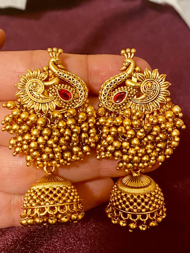 These Antique Peacock Earrings come in 4 different colors and are the perfect addition to your Indian outfit. With their unique and elegant design, these earrings will add a touch of charm to your ensemble. Crafted with attention to detail, they are a timeless piece that will elevate your style. Length - 6.5 cm Jewellery Care- Keep the jewelry dry, avoid heat and contact with perfumes & water. Peacock Earrings Indian Gold, Peacock Jewellery, Jhumkas Gold, Jhumka Set, Beautiful Gold Earrings, Gold Jhumka, Gold Jhumka Earrings, Gold Earrings Models, Peacock Earrings