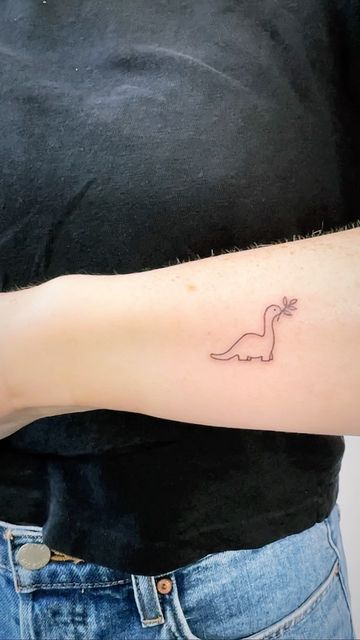 a person with a tattoo on their arm that has a small dinosaur drawn on it